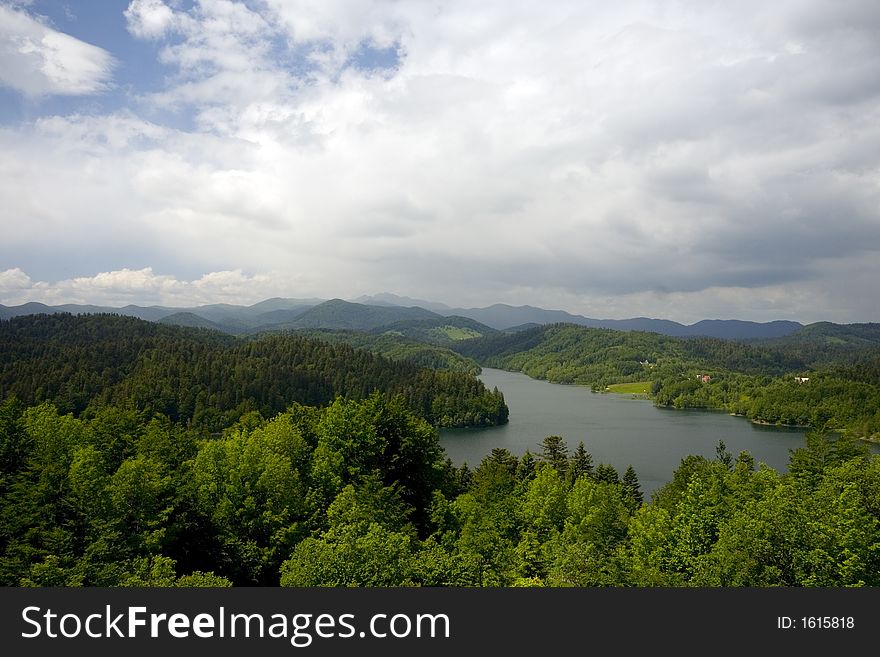 Lake surrounded with mountains with clouds