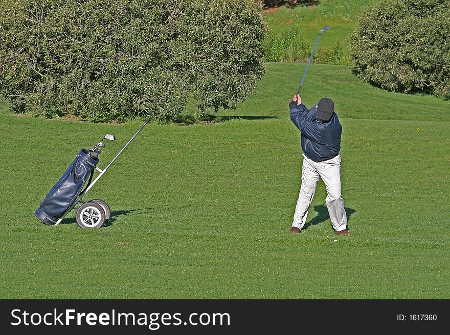 Golfer at top of swing on a golf course
