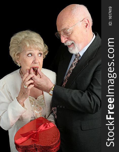A humorous picture of a husband feeding his wife Valentine candy. She doesn't look too sure about it. Black background. A humorous picture of a husband feeding his wife Valentine candy. She doesn't look too sure about it. Black background