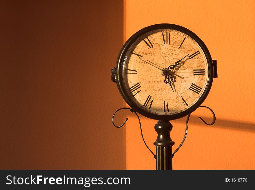 An antique clock with map face on a warm orange background.  Horizontal format. An antique clock with map face on a warm orange background.  Horizontal format.