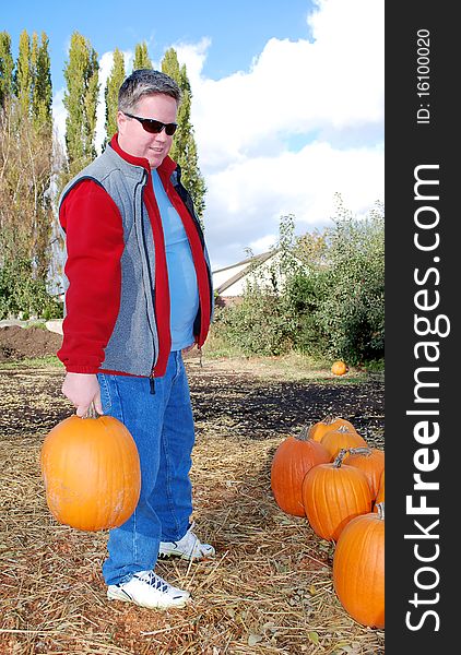 The man stands with pumpkin in his hands. The man stands with pumpkin in his hands.