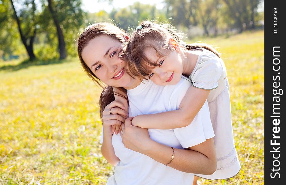 Beautiful young mother and her daughter in the park on a sunny autumn day. Beautiful young mother and her daughter in the park on a sunny autumn day