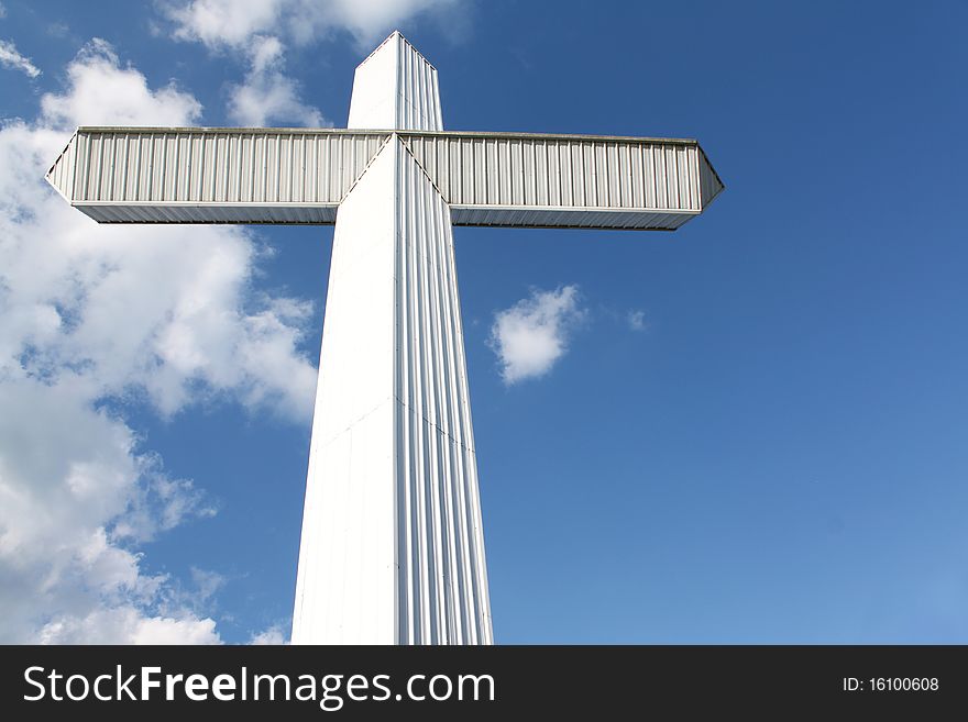 A massive white cross stands against a blue sky. Copy-space on the side for your message. A massive white cross stands against a blue sky. Copy-space on the side for your message.