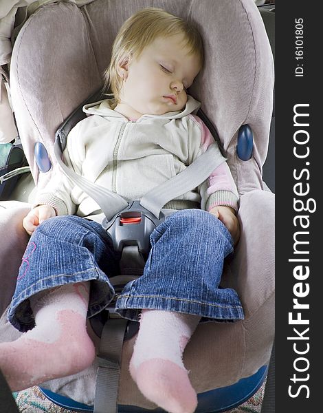 The small child fastened by seat belts sleeps in a car autoarmchair. The small child fastened by seat belts sleeps in a car autoarmchair