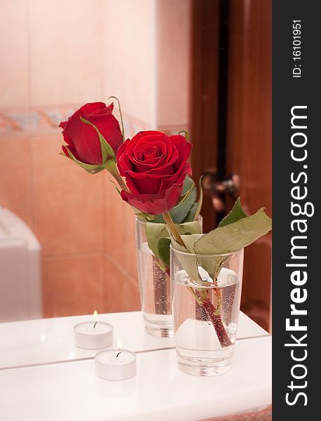 Rose with candle on mirror shelf in bathroom