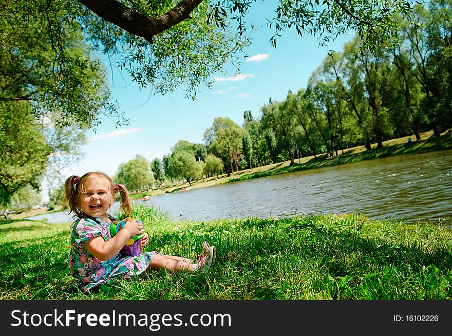 Happy girl sitting on river bank