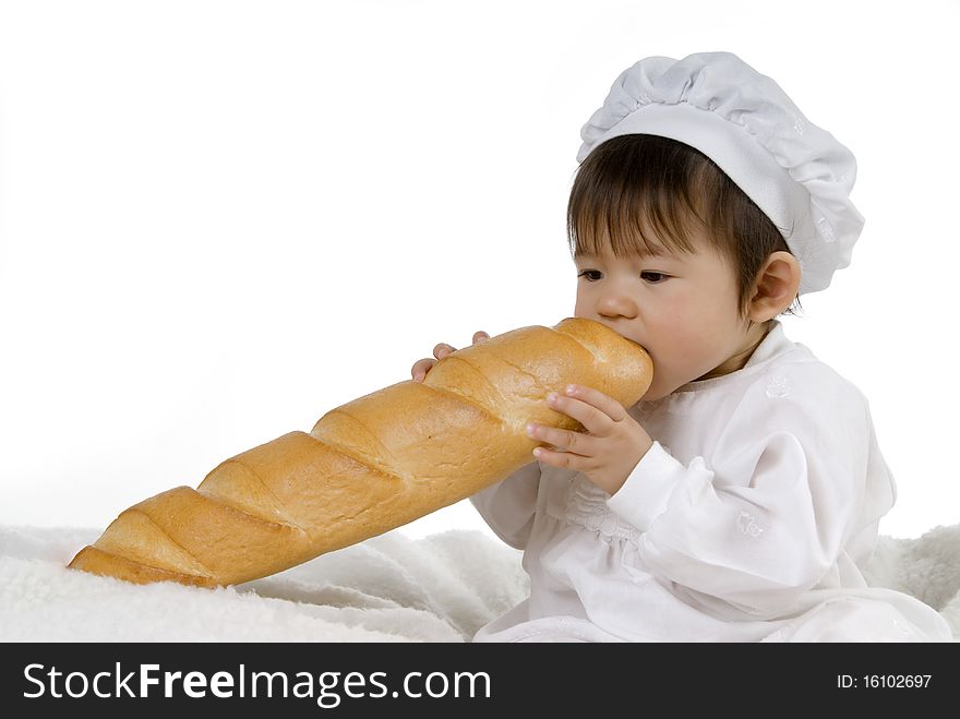 Cute baby in white cooking dress biting big baguette. Cute baby in white cooking dress biting big baguette