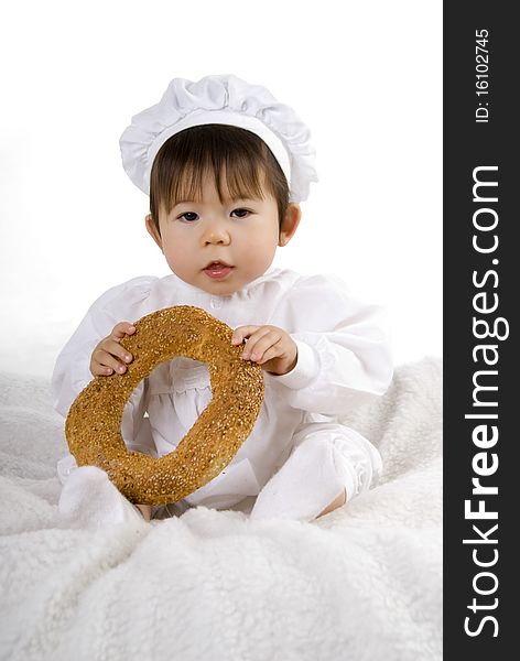 Little girl in the cook costume sitting with bread. Little girl in the cook costume sitting with bread