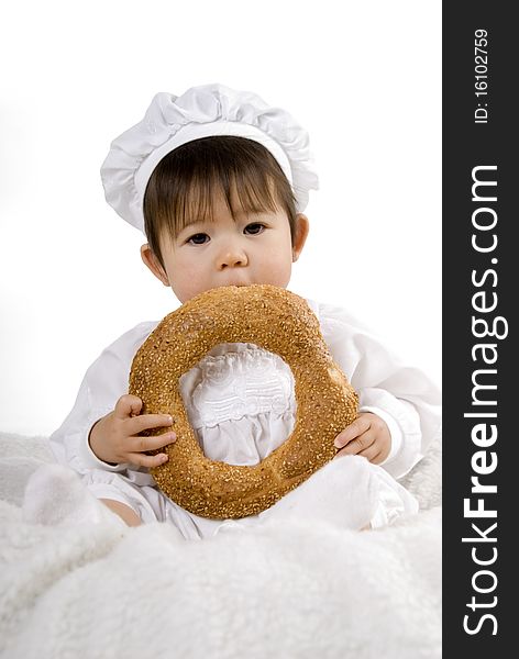 Little baby in chef dress sitting and eat bread. Little baby in chef dress sitting and eat bread