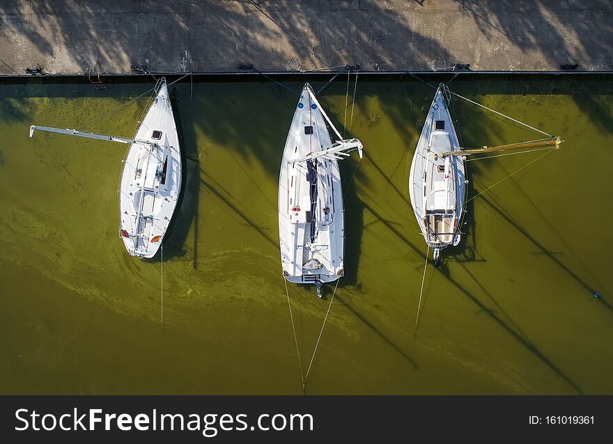 Pier with boats, marina lot. Aerial top view from drone. Green water due to seaweed.