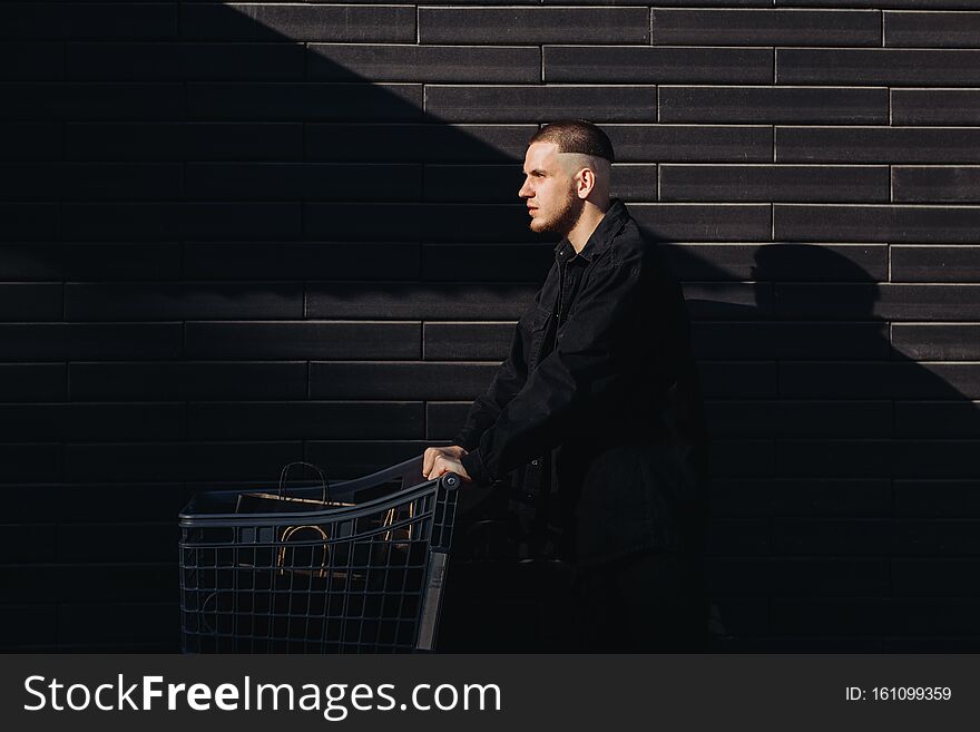 Stylish man in black with shopping bags  in a trolley on Black Friday