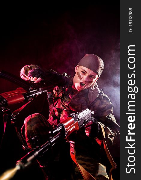 Screaming soldier shooting his enemies, studio shot over black background