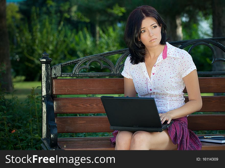 Young beautiful student girl with laptop in the park. Young beautiful student girl with laptop in the park