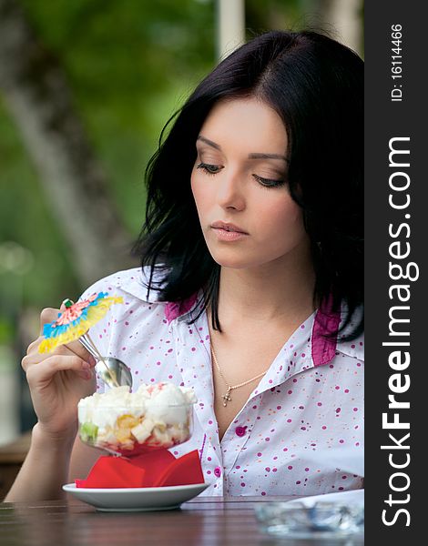 Young beautiful woman eating an ice cream in cafe. Young beautiful woman eating an ice cream in cafe
