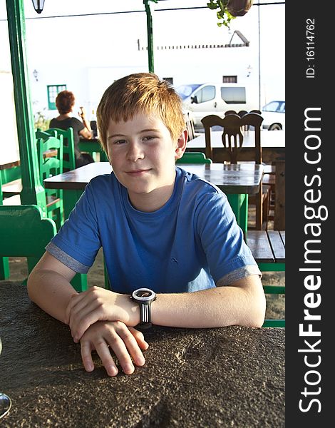 Young Boy Is Sitting On A Table In A Restaurant