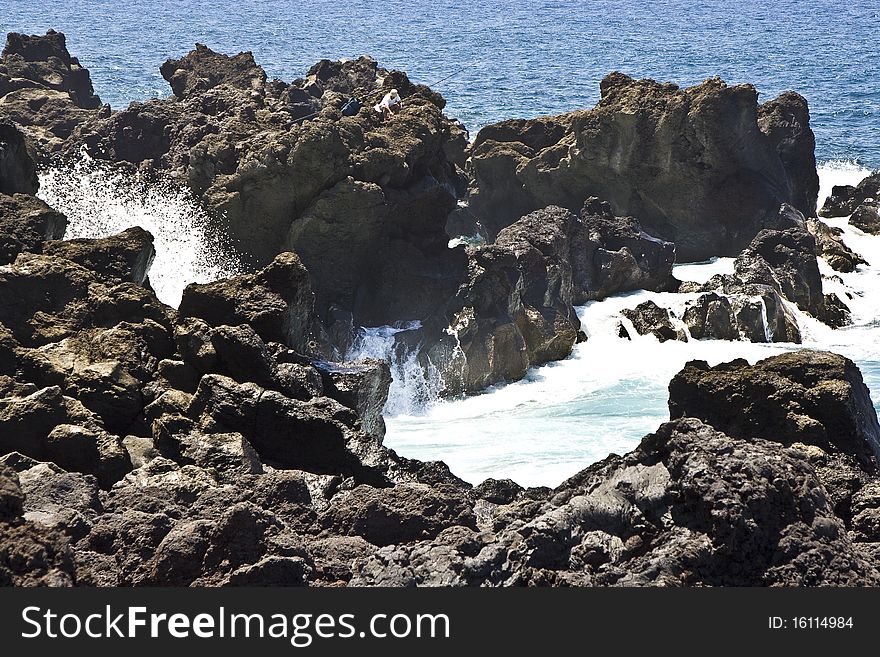 Angler on a cliff with rod in stormy sea, Lanzarote