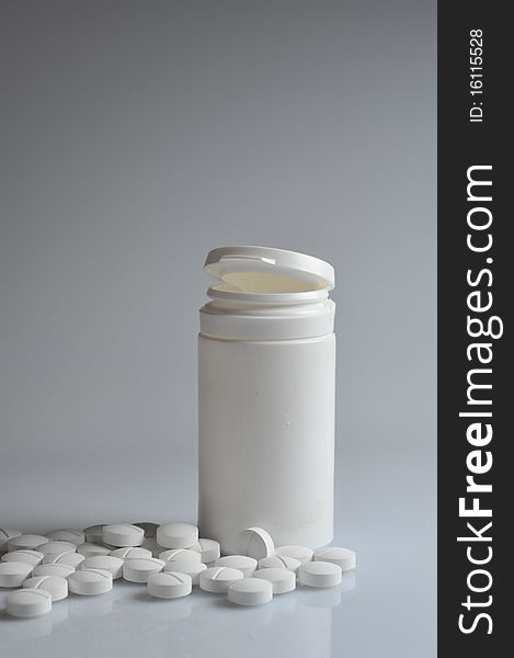 Open   prescription bottles  and white tablets  scattered on  table