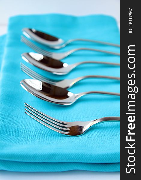 Cutlery forks and spoons on a blue napkin