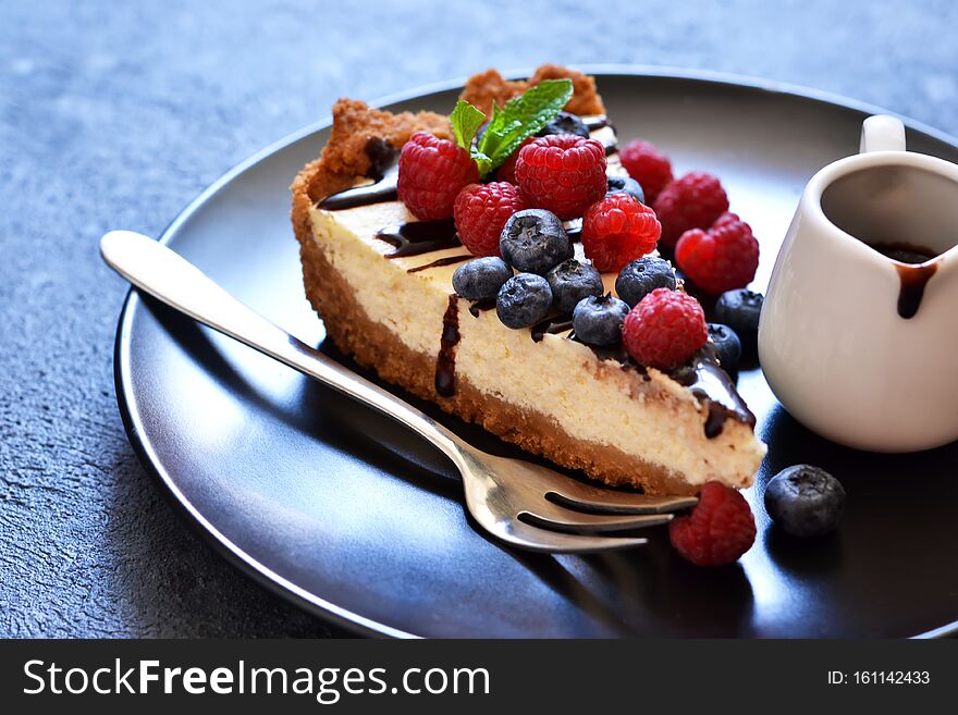 Homemade vanilla cheesecake with chocolate sauce and berries on a concrete background