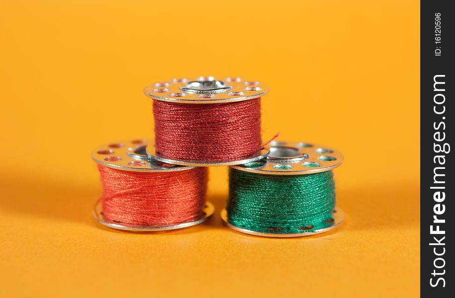 Colorful thread spools on orange background