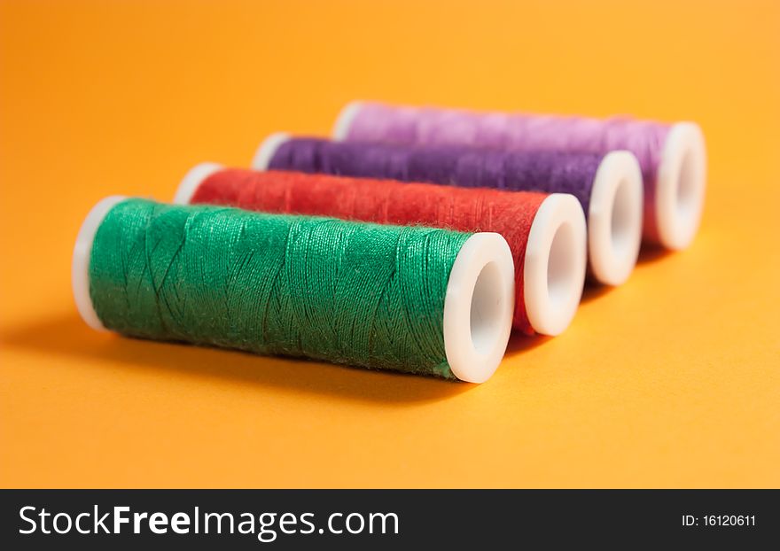 Colorful thread spools on orange background