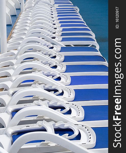 Blue sun loungers all in a line on a sunny deck. Blue sun loungers all in a line on a sunny deck.