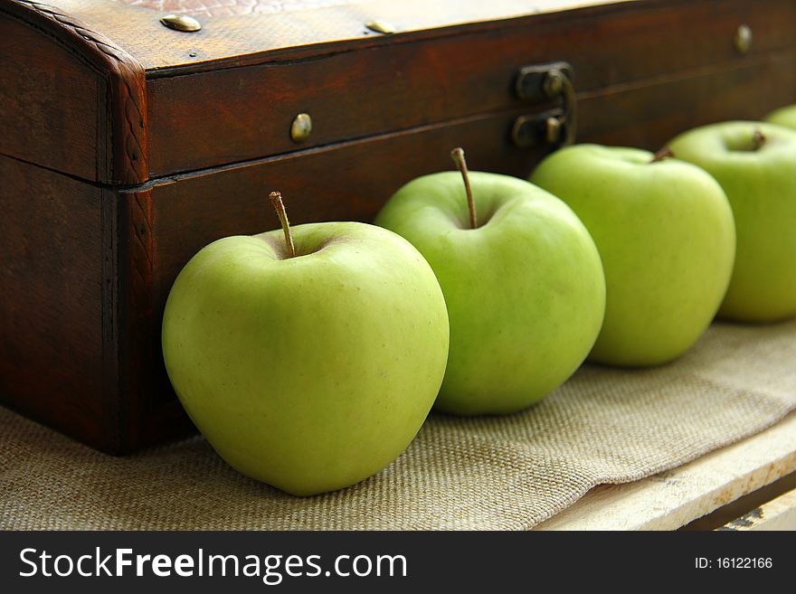 Green apples on the background of an old wooden chest