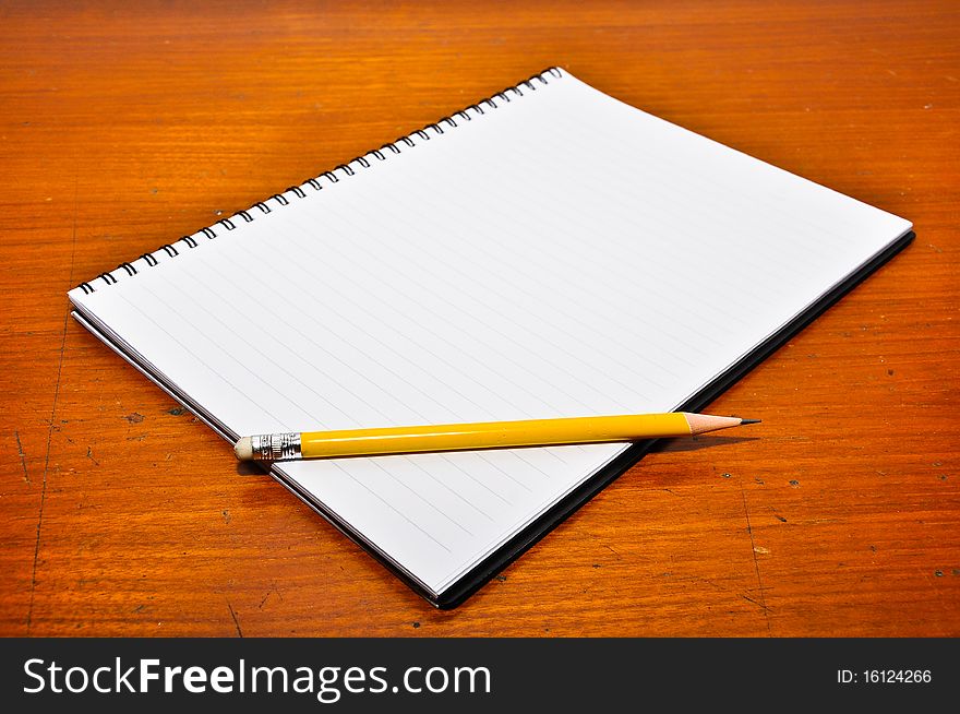 White Blank Notebook with yellow pencil on Wood Background