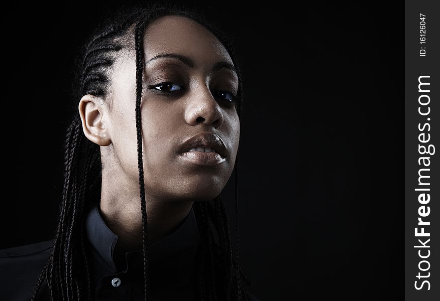 Portrait of a beautiful young black woman posing in black background.