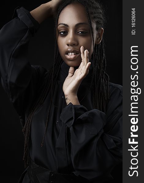 Portrait of a beautiful young black woman posing in black background.