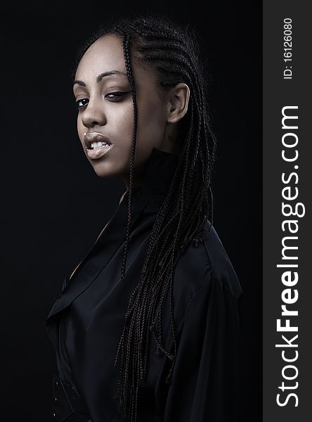 Portrait of a beautiful young black woman posing in black background.