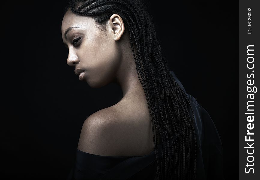 Portrait of a beautiful young black woman posing in black background.