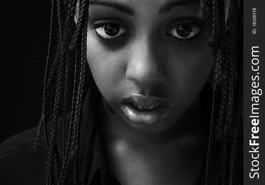 Portrait of a beautiful young black woman posing in black background.