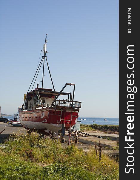 A small boat on dry land at the harbour in Lamlash on the Island of Arran, Scotland. A small boat on dry land at the harbour in Lamlash on the Island of Arran, Scotland