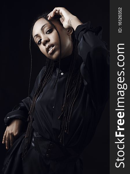 Portrait of a beautiful young black woman posing in black background.