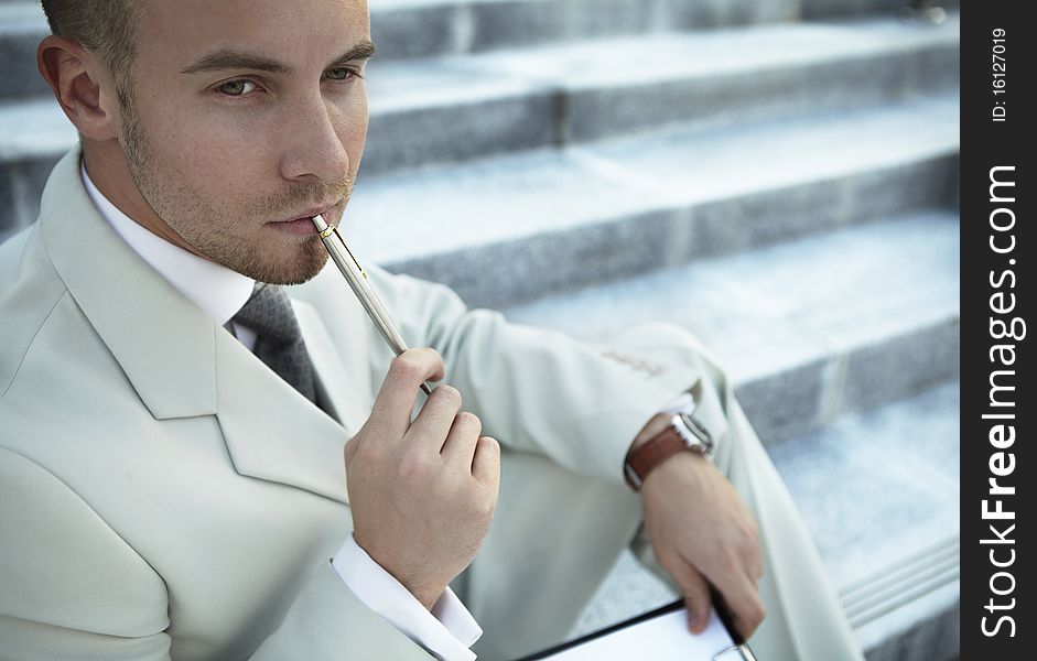 Handsome business man on the stairs reviewing his notes. Handsome business man on the stairs reviewing his notes