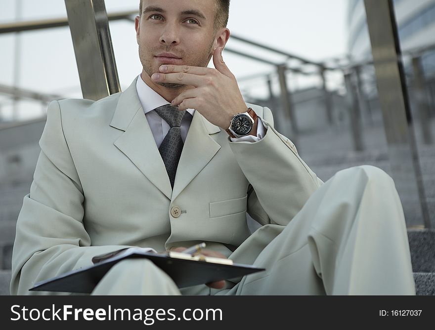 Handsome business man on the stairs reviewing his notes. Handsome business man on the stairs reviewing his notes