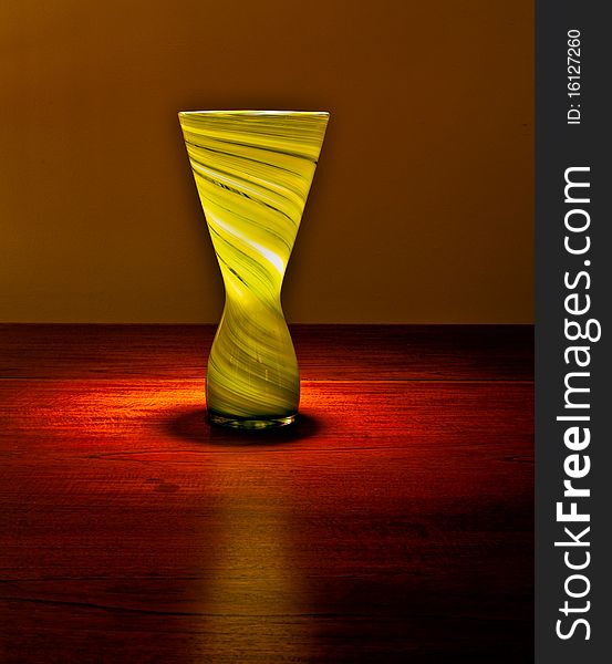 A glass vase on a table top. A glass vase on a table top.