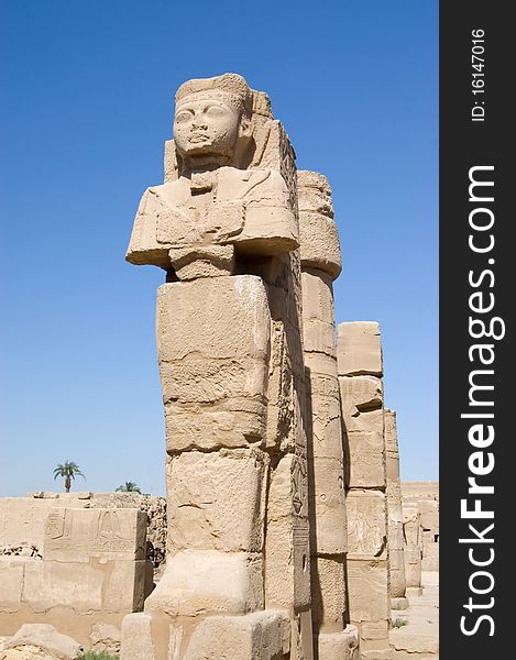 Ancient Pharaoh statue and column on backlighted sky background