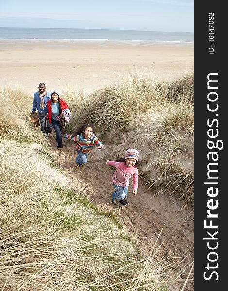 Family Walking Along Dunes On Winter Beach Smiling.