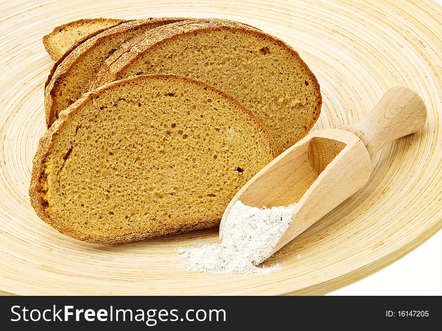 Rye bread on wooden plate and spoon of flour