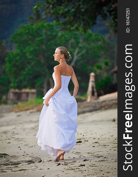 Bride walking along sea coast in the wedding dress