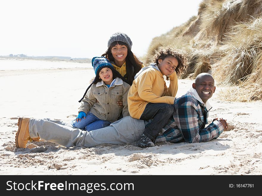 Family Sitting On Winter Beach Smiling
