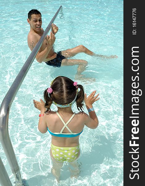 Father and daughter are playing in pool.