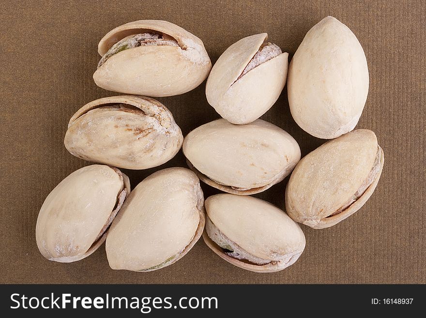 Shelled pistachios laying on a brown background.