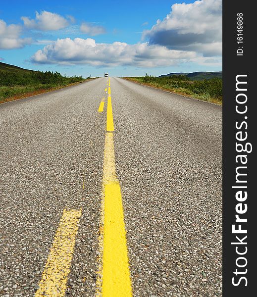 Asphalt road with yellow line is running away. Norwegian highway is photographed with diminishing perspective. Asphalt road with yellow line is running away. Norwegian highway is photographed with diminishing perspective.