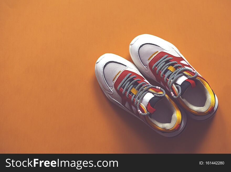 Multi-colored fashion sneakers on a orange background. Sport. There is a place for text