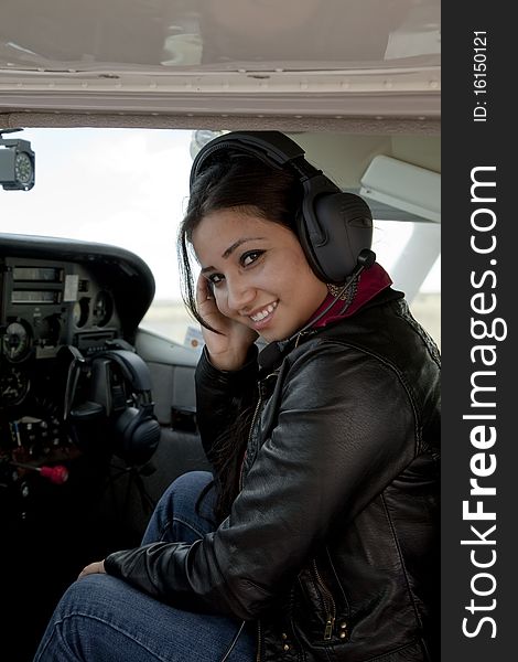 A woman in the cockpit of an airplane smiling. A woman in the cockpit of an airplane smiling.