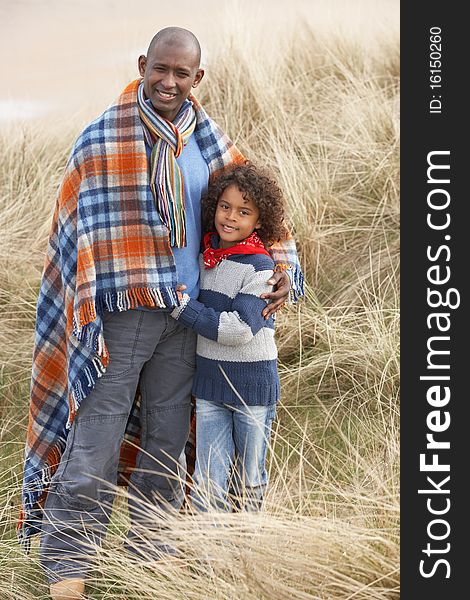 Father And Son Wrapped In Blanket Amongst Dunes On