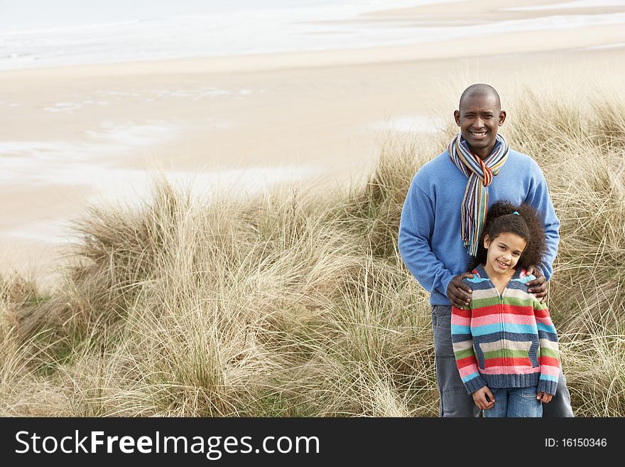 Father And Daughter Amongst Sand Dunes On Winter Beach Smiling. Father And Daughter Amongst Sand Dunes On Winter Beach Smiling